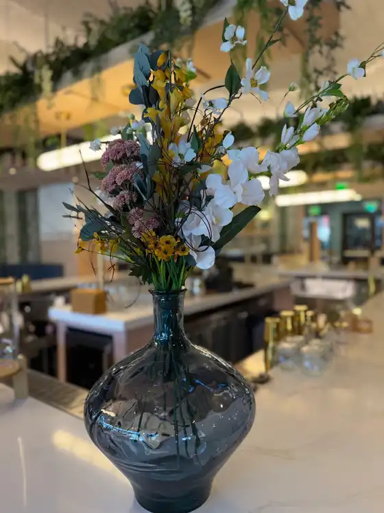 Close-up of a faux bar centerpiece with white dogwood branches, pink sedum and eucalyptus in smoked glass