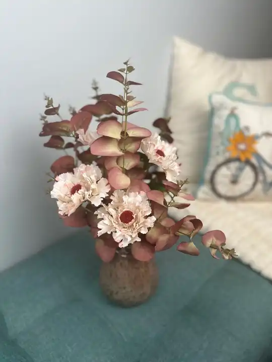 Blush dahlias and burgundy eucalyptus in an amber glass vase