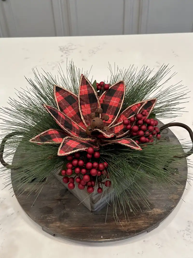 Buffalo plaid poinsettia centerpiece with red berries and pine on a wooden tray