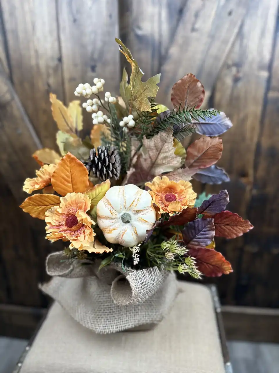 Fall arrangement of pumpkins, sunflowers and autumn leaves wrapped in burlap