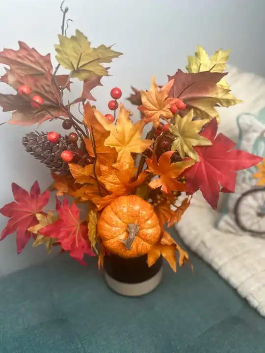 Maple leaves, pumpkin and berries in a bold orange fall arrangement