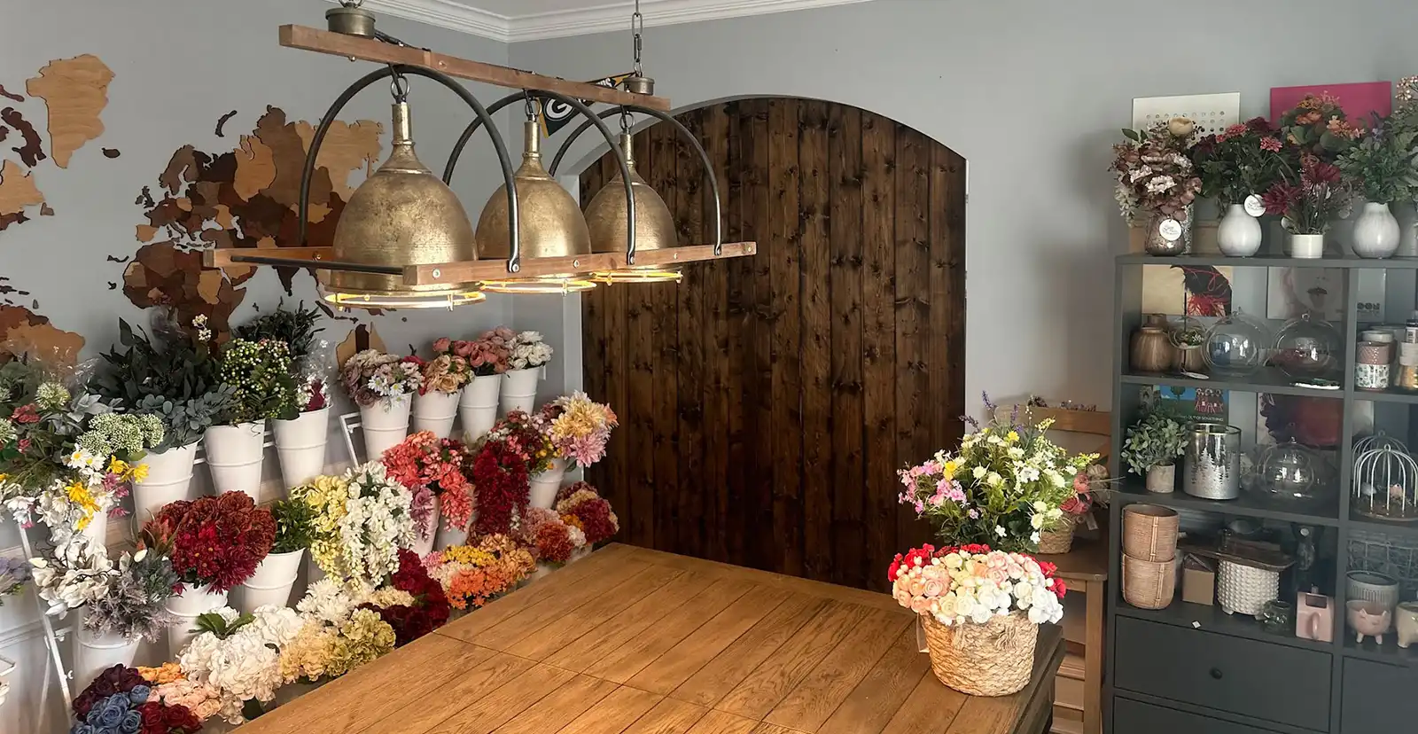 Sage Flowers design studio in Waxhaw with a wall of faux flower stems and a large worktable