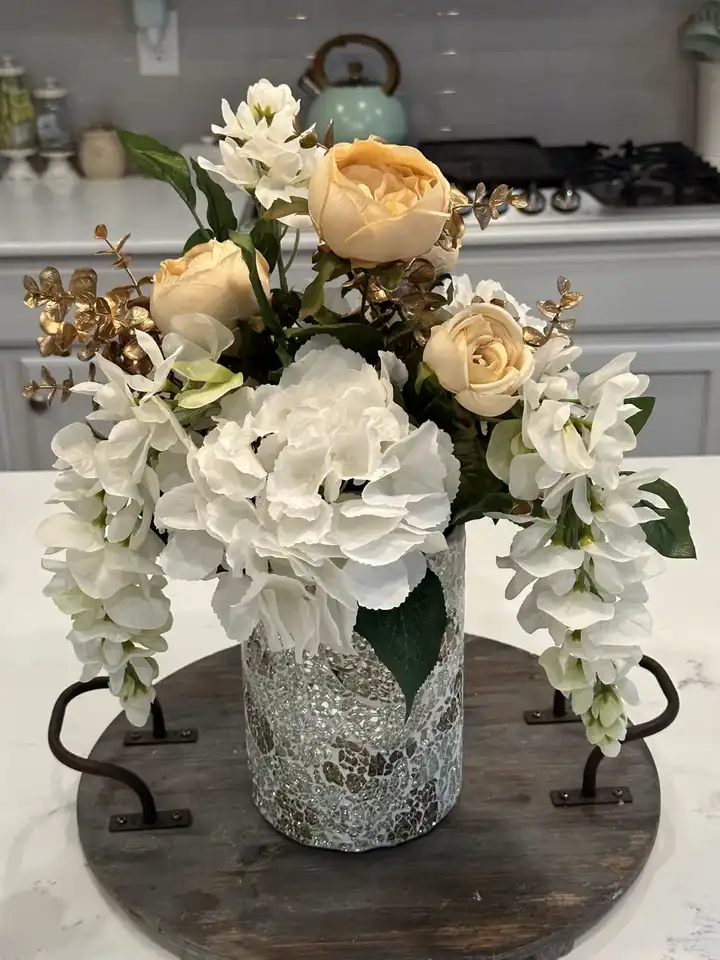 White hydrangea, cream roses and orchids in a mercury glass vase